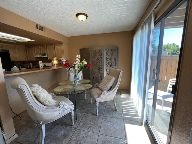 dining room featuring visible vents, a textured ceiling, and light tile patterned flooring