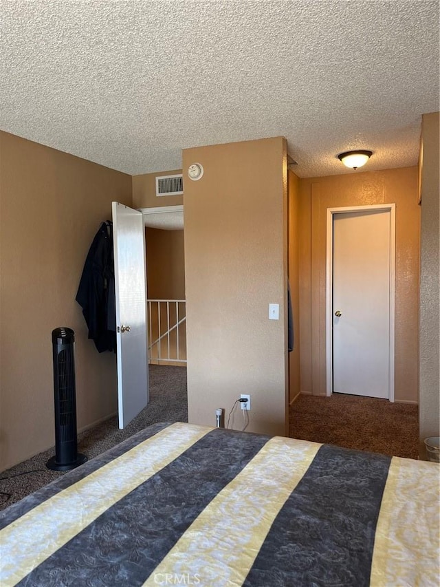 bedroom featuring visible vents, carpet, and a textured ceiling
