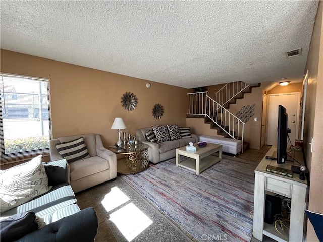 living room with visible vents, a textured ceiling, and stairway