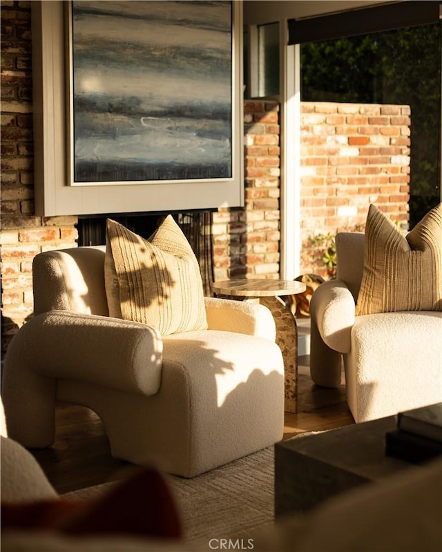 living area featuring wood finished floors and brick wall