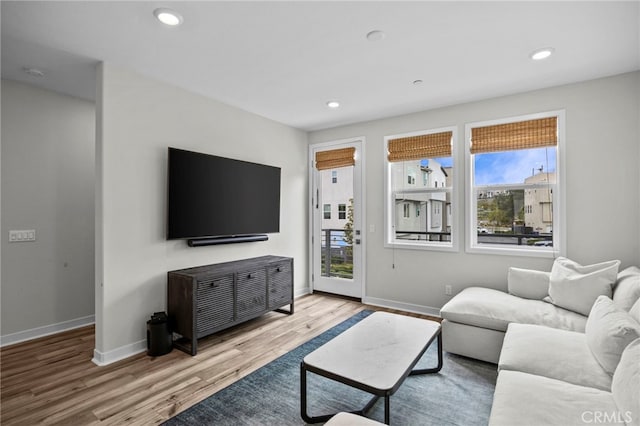 living area with baseboards, recessed lighting, wood finished floors, and a healthy amount of sunlight