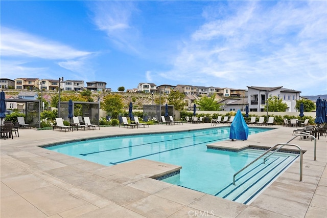 pool with fence, a patio area, and a residential view