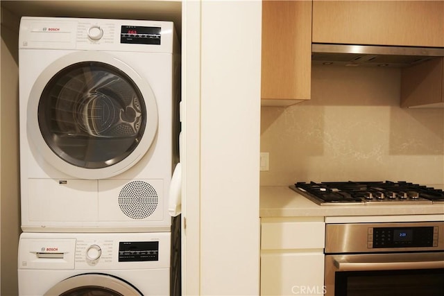 clothes washing area with stacked washer and clothes dryer and laundry area