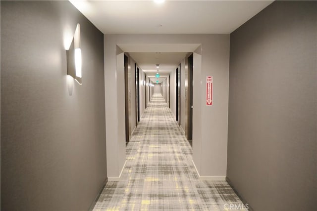 corridor with baseboards and light carpet