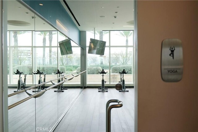 exercise room with a wall of windows and wood finished floors