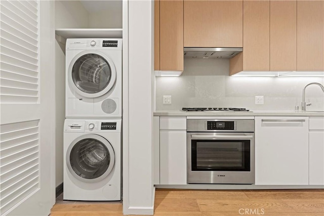877 Francisco St Unit 1723, Los Angeles, CA 90017 - washroom featuring stacked washer / drying machine and light wood finished floors