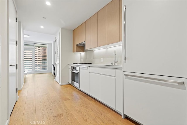 877 Francisco St Unit 1723, Los Angeles, CA 90017 - kitchen featuring white fridge, stainless steel oven, light wood-type flooring, under cabinet range hood, and light countertops