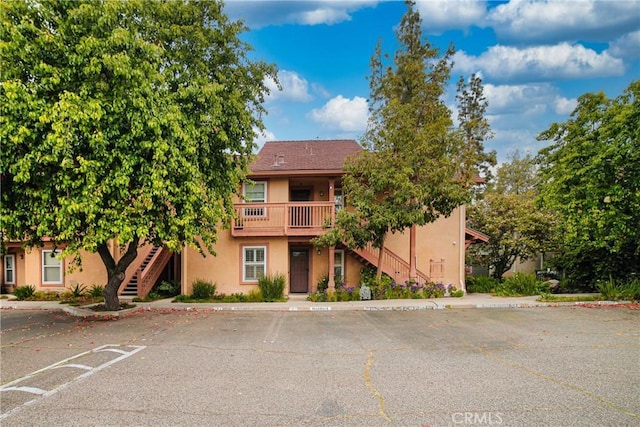 view of front of home with uncovered parking, stairs, and stucco siding