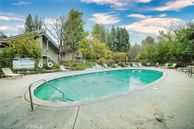 community pool with a patio area and fence
