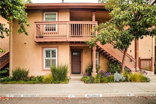 view of front of house featuring stairway, a balcony, and stucco siding