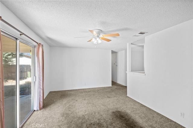 empty room featuring a textured ceiling, ceiling fan, visible vents, and carpet