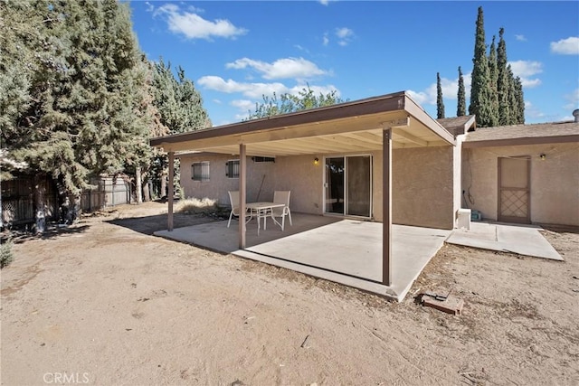 rear view of house featuring fence, stucco siding, and a patio area