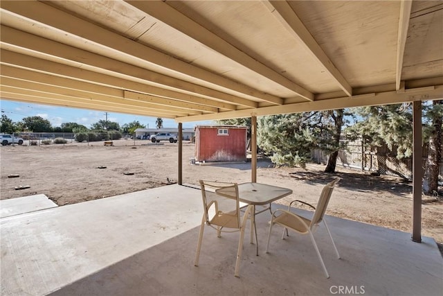 view of patio / terrace with a storage shed, fence, an outbuilding, and outdoor dining space