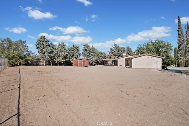 view of yard featuring an outdoor structure, fence, and a storage shed