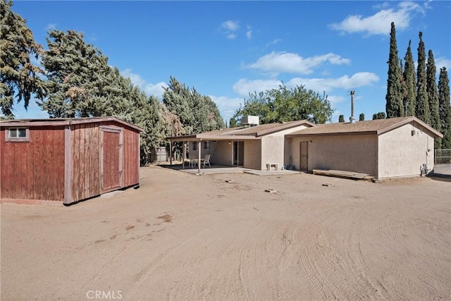 rear view of house with a storage shed, an outbuilding, and a patio area