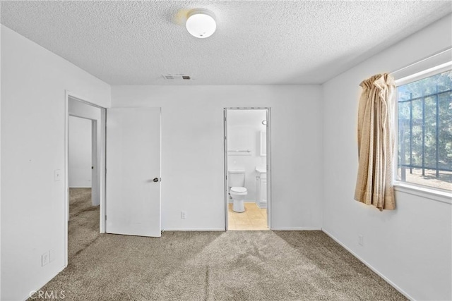 unfurnished bedroom with carpet, connected bathroom, a textured ceiling, and visible vents