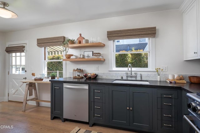 bar with a sink, light wood-style floors, and stainless steel appliances