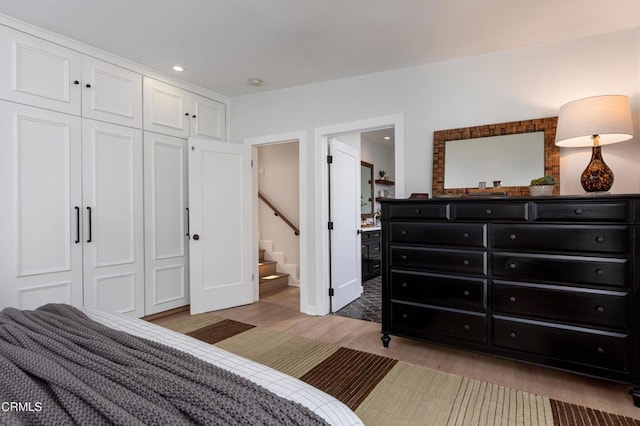 bedroom featuring a closet, connected bathroom, light wood-style flooring, and recessed lighting