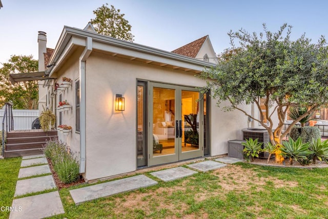 back of property with a lawn, a chimney, and stucco siding