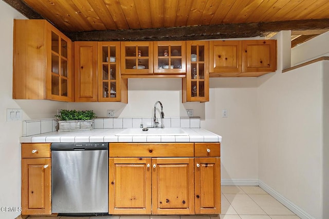 kitchen with stainless steel dishwasher, baseboards, wooden ceiling, a sink, and light tile patterned floors