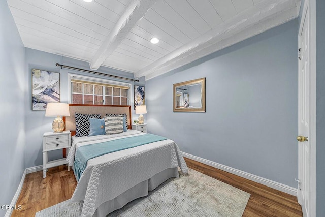 bedroom with baseboards, wood ceiling, beam ceiling, and wood finished floors