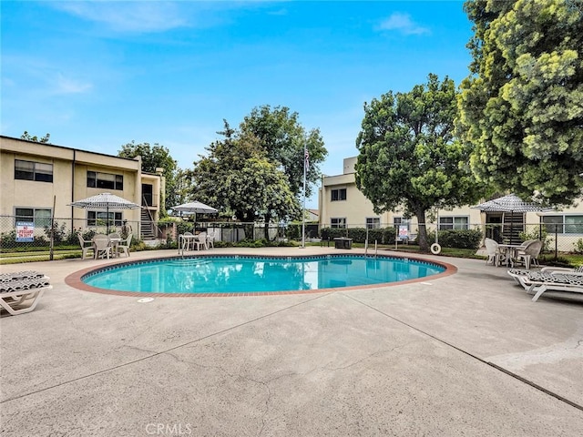 community pool with a patio and fence