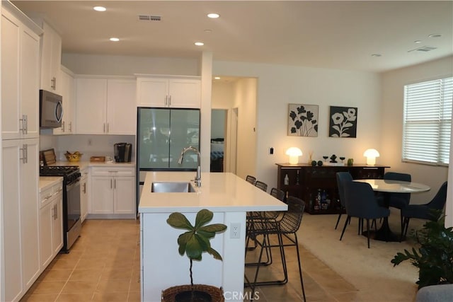 4211 E Malagon Privado Unit 66, Ontario, CA 91761 - kitchen with black gas range, visible vents, a center island with sink, white cabinetry, and a sink