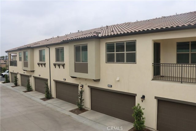 4211 E Malagon Privado Unit 66, Ontario, CA 91761 - view of side of home featuring a tiled roof, an attached garage, and stucco siding