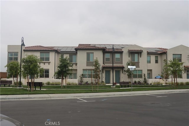 4211 E Malagon Privado Unit 66, Ontario, CA 91761 - exterior space with stucco siding, a tiled roof, and solar panels