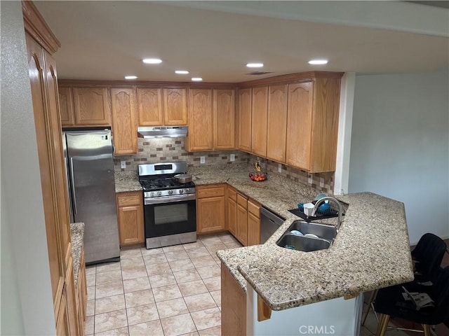7548 Chase Ave, Hesperia, CA 92345 - kitchen with appliances with stainless steel finishes, a sink, under cabinet range hood, a peninsula, and tasteful backsplash