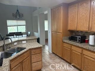 7548 Chase Ave, Hesperia, CA 92345 - kitchen with stainless steel microwave, a sink, a chandelier, and light stone counters
