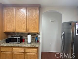7548 Chase Ave, Hesperia, CA 92345 - kitchen with appliances with stainless steel finishes, arched walkways, light stone counters, and wood finished floors