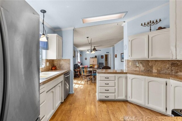 kitchen featuring a peninsula, white cabinets, tasteful backsplash, light wood finished floors, and stainless steel appliances