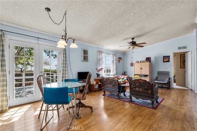 dining area with ceiling fan, a textured ceiling, visible vents, crown molding, and light wood-type flooring