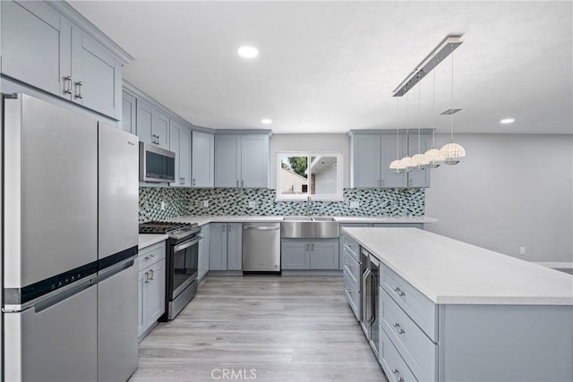 kitchen featuring wine cooler, a sink, light countertops, appliances with stainless steel finishes, and gray cabinets