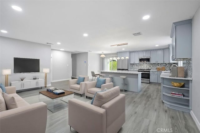 living room featuring light wood-style flooring, visible vents, and recessed lighting