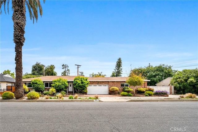 ranch-style house with fence, an attached garage, and driveway