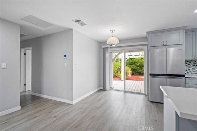 unfurnished dining area featuring light wood-type flooring, baseboards, and visible vents