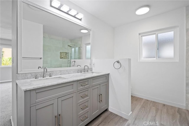 bathroom with baseboards, a shower stall, and a sink