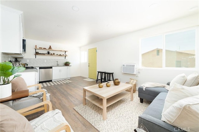 living room featuring light wood finished floors and a wall unit AC