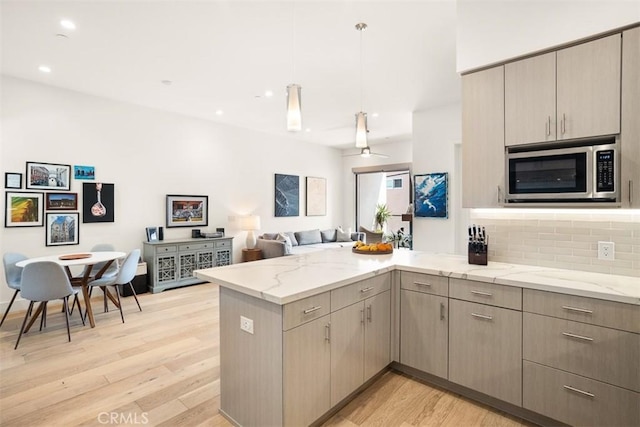 4322 Gentry Ave Unit 104, Studio City, CA 91604 - kitchen with a peninsula, open floor plan, stainless steel microwave, light stone counters, and light wood finished floors