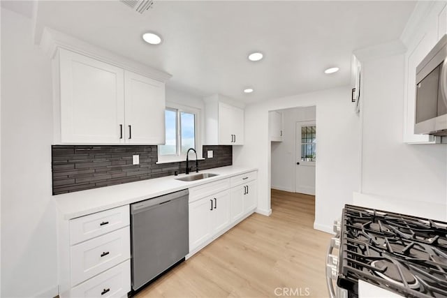 4832 Olive St, Montclair, CA 91763 - kitchen featuring visible vents, white cabinetry, a sink, backsplash, and stainless steel appliances