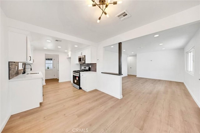 4832 Olive St, Montclair, CA 91763 - kitchen with visible vents, decorative backsplash, a sink, light wood-style flooring, and appliances with stainless steel finishes