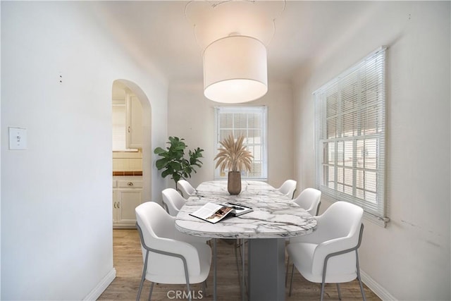 3712 Virginia Rd, Los Angeles, CA 90016 - dining space with baseboards, arched walkways, wood finished floors, and a healthy amount of sunlight