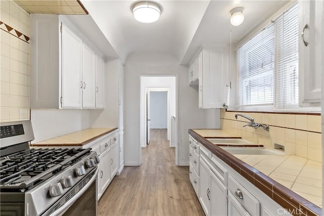 3712 Virginia Rd, Los Angeles, CA 90016 - kitchen with tile counters, a sink, white cabinets, and stainless steel gas range