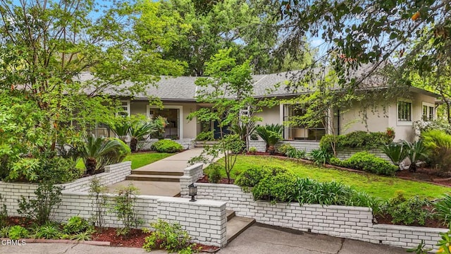ranch-style house featuring roof with shingles and stucco siding