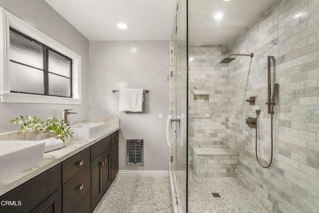 full bath with visible vents, double vanity, baseboards, a shower stall, and a sink