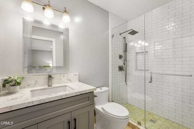 bathroom featuring vanity, a shower stall, and toilet