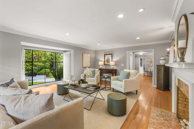 living area with crown molding, recessed lighting, light wood-style flooring, and a fireplace