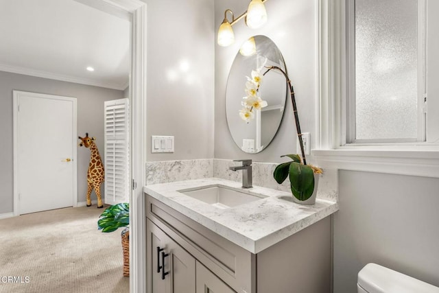 bathroom with vanity, ornamental molding, baseboards, and toilet